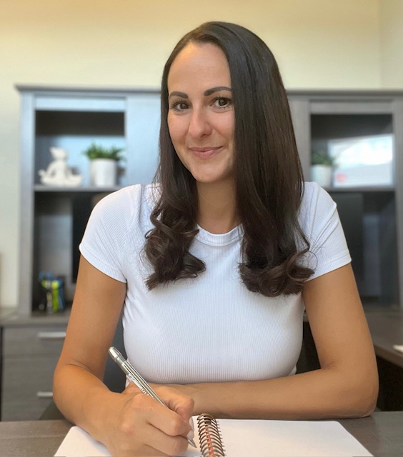 Contact page photo. Woman sitting at her desk writing.